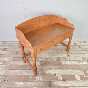 A country-style vintage pine washstand with two drawers and a shaped gallery back, raised on four turned legs. A stunning rustic piece suited to bathroom use as a washstand or placed in a bedroom as a dressing table.