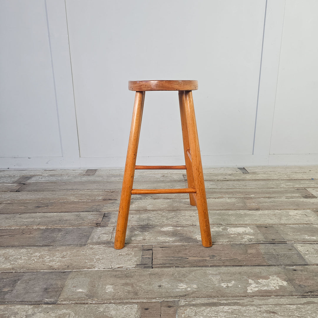 Oval-seated stool crafted from elm, reflecting mid-century aesthetics.
