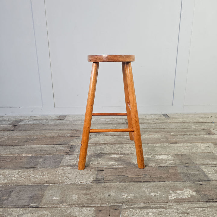 Oval-seated stool crafted from elm, reflecting mid-century aesthetics.
