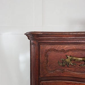 Antique French serpentine commode in walnut, dating from the 19th century, showing four full-width drawers fitted with original brass hardware and set on cabriole legs.
