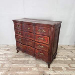 Antique French walnut chest of drawers with a serpentine front, four drawers arranged one above the other, and ornate brass handles with matching escutcheons.
