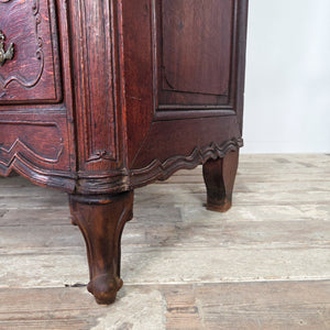 Antique French walnut commode with serpentine drawer fronts, four graduating drawers, and decorative brass plate drop handles and escutcheons.
