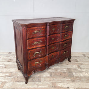 French 19th century walnut chest of drawers in Louis XV style, featuring a serpentine front, ornate brass hardware, and a shaped lower apron.

