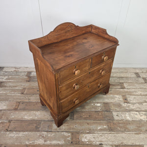 A 19th-century Victorian pine storage chest in a two-over-two design with matching wooden knobs. The shaped gallery and bracket feet give this farmhouse style piece a functional, cottage style feel suitable for clothes, linens or everyday storage.