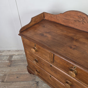 A Victorian pine four-drawer chest in a rustic farmhouse style, finished in darker wax. Its two-over-two configuration, gallery top and wooden knobs make it a functional country house style storage chest for clothing or household items.