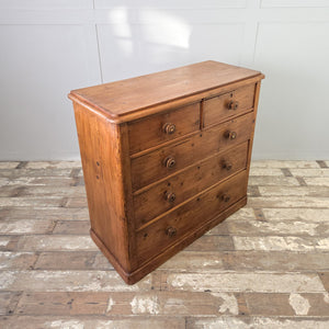 A country house style Victorian pine storage chest in a two-over-three arrangement, featuring original decorative knobs and a wax-sealed patina. Its rustic pine construction and plinth base make it a substantial cottage style storage piece.