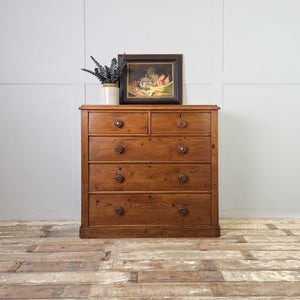 A wax-sealed Victorian pine chest of drawers with five spacious drawers, original round knobs and a plinth base. The rustic pine and rich patina give it a farmhouse style feel, offering versatile storage around the home.