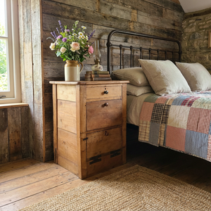 An early 20th century antique workshop drawer unit constructed from mixed timbers, with two drawers and a lower cupboard accessed via a hinged drop-down door with large metal hinges. A practical industrial-style piece that works well as a bedside table in the bedroom or as an end table in the hallway or living room.