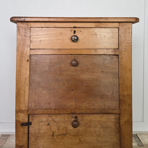 An antique early 20th century workshop drawer unit with two drawers above a lower cupboard accessed via a hinged drop-down door. Constructed from mixed timbers and finished in rustic pine wax, this industrial-style piece works well as a bedside table in the bedroom or as an end table in the hallway or living room.