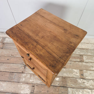Antique workshop drawers dating from the early 20th century, made from mixed timber with two drawers and a lower cupboard concealed behind a drop-down front. Finished in rustic pine wax, this industrial piece is well suited for use as a bedside table in the bedroom or an end table in the hallway or living room.