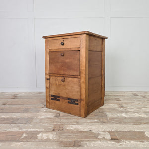 An early 20th century antique workshop drawer unit with two drawers and a small lower cupboard accessed via a hinged drop-down door. Constructed from mixed timbers with large metal hinges, this industrial-style piece works well as a bedside table in the bedroom or as an end table in the hallway or living room.