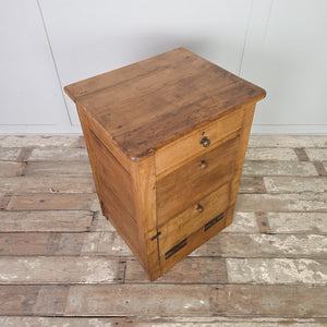 Early 20th century antique workshop drawers featuring two drawers and a lower cupboard with a hinged drop-down front. Built from mixed timber and sealed in rustic pine wax, this industrial-style drawer unit works well as a bedside table in the bedroom or as an end table in the hallway or living room.