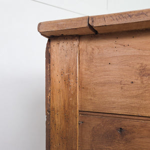 An early 20th century antique workshop drawer unit built from mixed timber, offering two drawers for storage and a lower cupboard accessed via a hinged drop-down door. With its rugged industrial character, it works well as a bedside table in the bedroom or as an end table in the hallway or living room.
