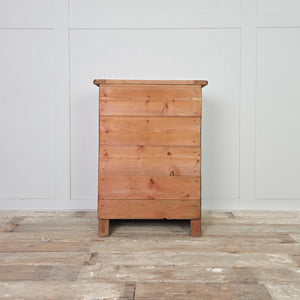 An antique early 20th century workshop drawer unit made from mixed timber, with two drawers and a lower cupboard accessed via a hinged drop-down door. The industrial-style design and rugged construction make it a practical option for use as a bedside table in the bedroom or an end table in the hallway or living room.