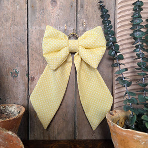 Handmade decorative fabric bow by Jennings & Cox, created from vintage yellow patterned fabric. Featuring a padded structure, long tapering tails, and brass hanging ring, each Country House Bow is unique and versatile for styling.