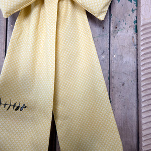 Handmade Country House Bow crafted from vintage yellow patterned fabric with a structured padded form. Featuring long tapering tails and a brass hanging ring, each bow is individually handmade and ideal for rustic home décor.