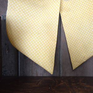 A handmade decorative fabric bow from the Jennings & Cox Country House collection, made from vintage yellow patterned fabric. Each bow is padded, shaped with elongated tails, and completed with a brass hanging ring, created in limited numbers.
