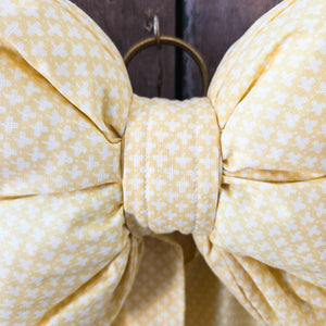 Handmade decorative bow from Jennings & Cox, crafted in vintage yellow patterned fabric with a padded design and long tapering tails. Finished with a brass ring, this Country House Bow is designed for rustic interiors, mantels, or doors