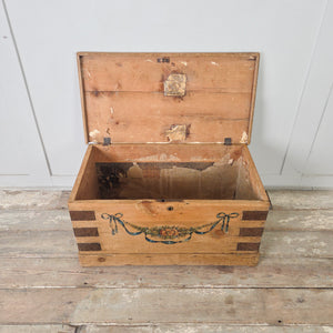 Antique French blanket chest with hand-painted blue ribbon and floral garland to the front panel and hinged lid
