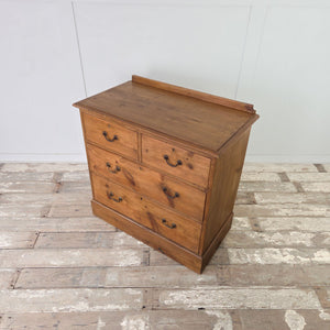 Rustic pine four drawer chest with low back upstand, brass swan neck handles and simple plinth base