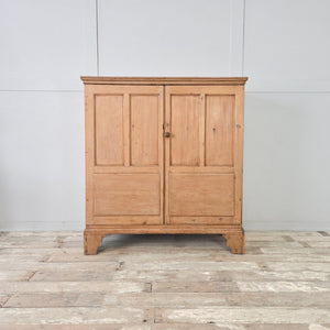 Georgian pine two door cupboard with panelled doors, moulded cornice, and shaped bracket feet, dating from the 18th century.
