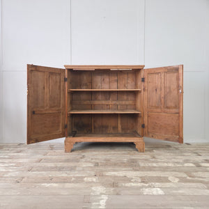 Antique pine cupboard with two panelled doors opening to three tiers of interior shelving, raised on bracket feet.
