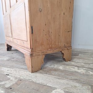 Antique two door pine linen cupboard with original lock and key, standing on shaped bracket feet, early 19th century.