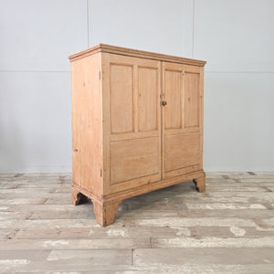 18th to early 19th century pine cupboard with two panelled doors, a moulded cornice, and shaped bracket feet.
