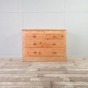 Antique Victorian pine four drawer chest arranged two over two, with contrasting wooden knobs, simple keyholes and plinth base.
