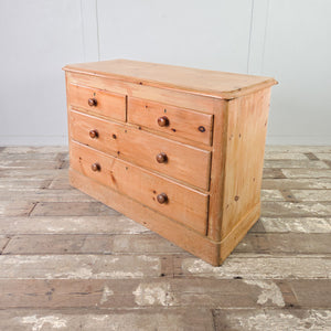 Victorian pine bedroom drawers in a two over two layout with turned wooden handles and simple centred escutcheons.

