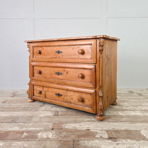 Early 20th century continental pine chest of drawers with three full-width drawers, carved detailing and turned wooden knobs.