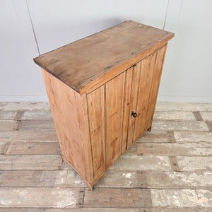 Vintage pine storage cupboard cabinet featuring vertical planked doors, fixed shelving inside, and a simple overhanging cornice above bracket style feet.