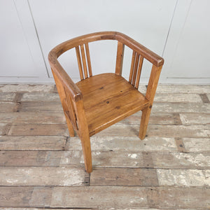 Pair of early 20th century pine armchair tub chairs with continuous curved top rail, vertical slat supports, deep pine seats, and square-set legs for farmhouse occasional seating.
