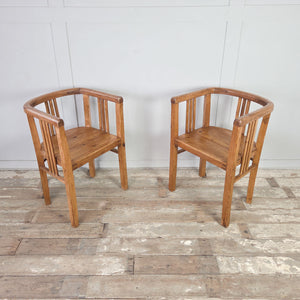 Two vintage pine tub chairs, early 20th century, with barrel-back shape, curved top rail around arms and back, vertical slat supports and deep pine seats on square-set legs.
