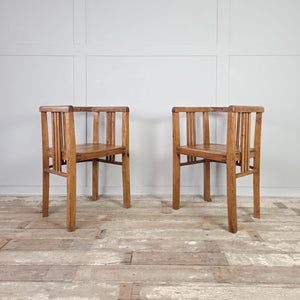 Matching pair of early 20th century pine armchairs in tub chair form, with continuous curved rail, slatted back and sides, deep seats, and square-set legs for occasional seating.
