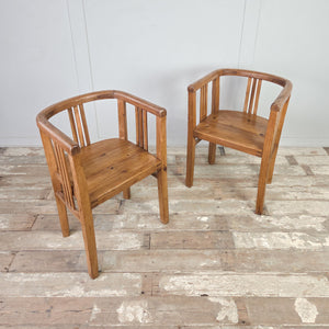 Pair of vintage pine reading chairs with tub chair silhouette, early 20th century, featuring a continuous curved top rail, slatted sides and back, deep seats and square-set legs.
