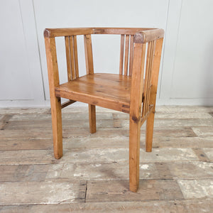 Rustic farmhouse pair of early 20th century pine tub chairs, built with barrel-back outline, continuous curved rail, slatted back and sides, deep seats and square-set legs.
