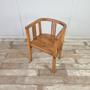Two early 20th century pine framed tub chairs with curved top rail forming the arms and back, vertical slat supports, deep pine seats and square-set legs