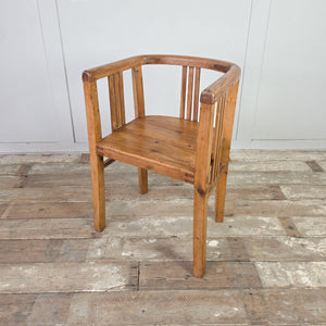 Pair of antique pine tub chairs in early 20th century style, with barrel-back silhouette, curved rail around the back and arms, slatted sides and back, and deep seats.
