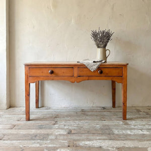 Antique Victorian pine prep table with a timeworn three plank top and two drawers with turned knobs
