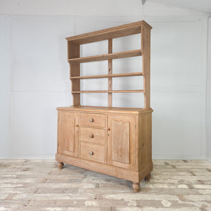 19th century English pine kitchen dresser with panelled cupboard doors and open shelving above
