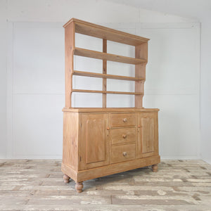 Antique farmhouse pine dresser with three shelf open rack and two flanking cupboard doors
